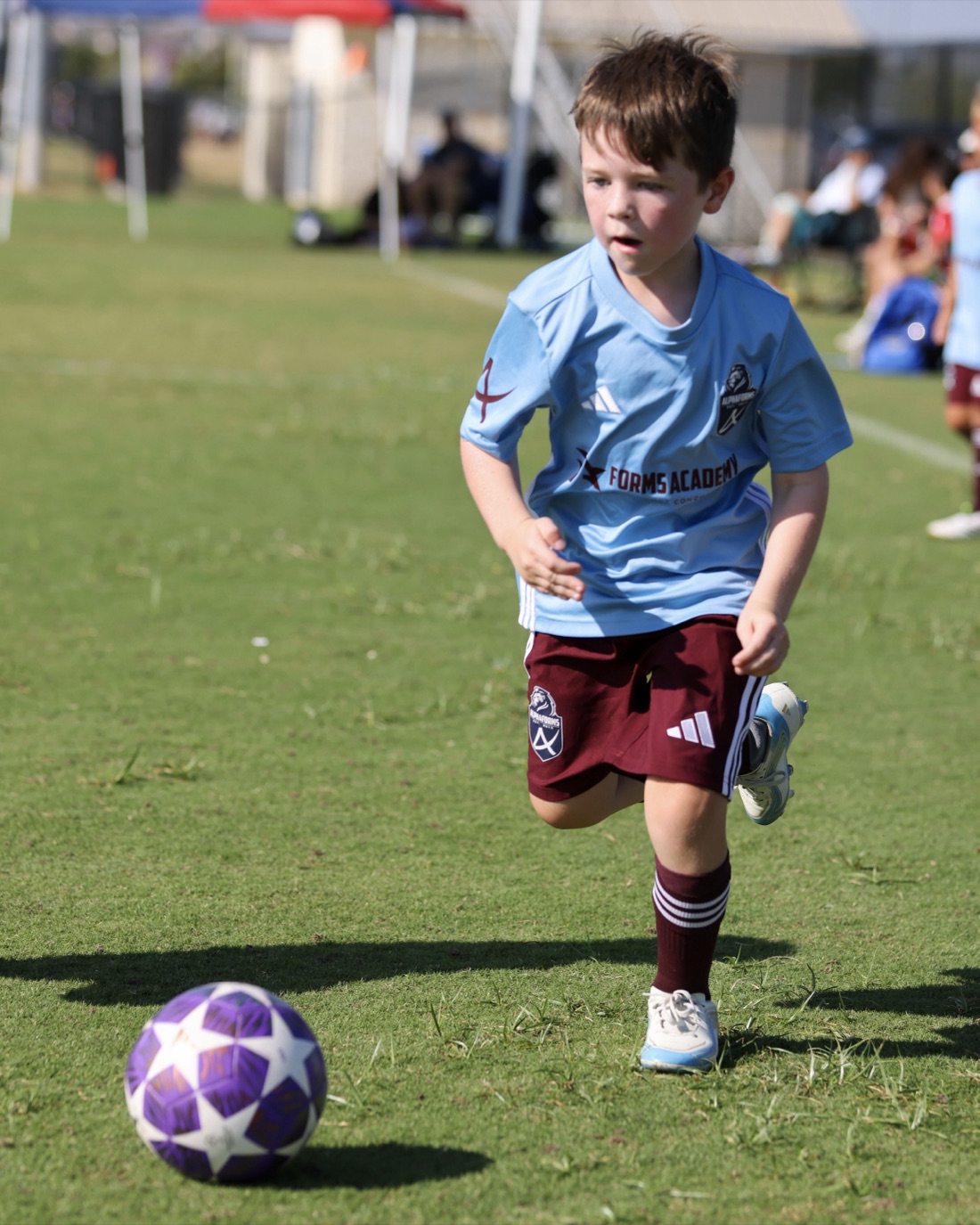 A Forms Academy player chasing the ball in a match
